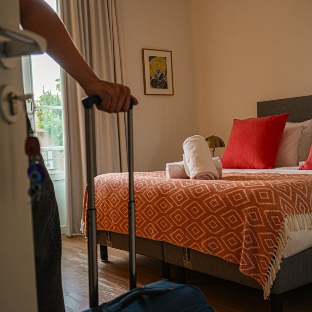 Voyageur rentre avec sa valise dans un logement préparé avec soin, la serviette roulée sur le lit